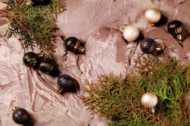 Christmas New Year background in the 2025 color of the year, Mocha Mousse. Christmas decorations balls and green branches on a background made from nerikomi-style raw clay mixture. Top view. clipart