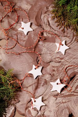 Christmas New Year background in the 2025 color of the year, Mocha Mousse. Christmas decorations white handcrafted porcelain stars, green branches on nerikomi-style raw clay mixture surface. Top view. clipart