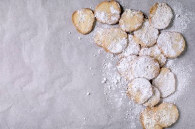 Homemade shortbread cookies dusted with powdered sugar, food background. A true rustic dessert, homemade pastry with sieve on white baking paper. Top view, copy space clipart