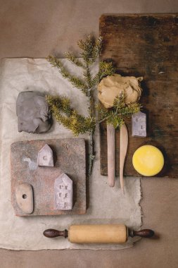 Yaratıcı tasarım bej çanak çömlek modu. Çiğ kil parçaları, doğal malzemeler, seramikçi aletler. Üst manzara, şablon, DIY seramikleri minyatür evler.