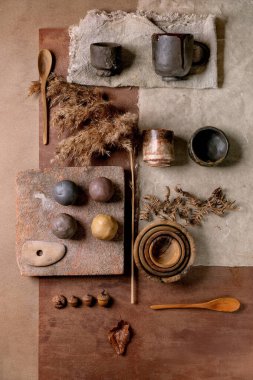 Yaratıcı tasarım bej çanak çömlek modu. Farklı renkte toplar, doğal malzemeler, seramik çay fincanları. Üst manzara, şablon, DIY seramik. Yıl Rengi 2025 Mocha Mousse