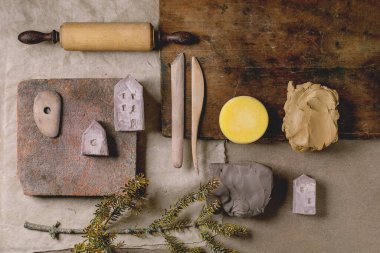 Yaratıcı tasarım bej çanak çömlek modu. Çiğ kil parçaları, doğal malzemeler, seramikçi aletler. Üst manzara, şablon, DIY seramikleri minyatür evler.