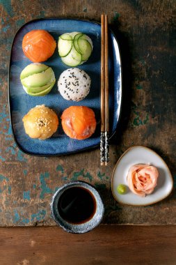 Temari suşi. Somon, avokado, salatalık ve Japon omletli suşi topları mavi tabakta. Soya sosu, zencefil turşusu, kırsal ahşap masada çubuklar. Üst görünüm
