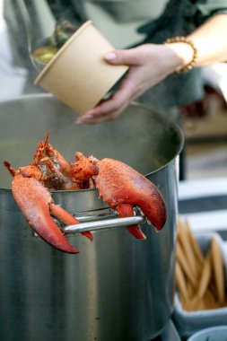 Avrupa sokak yemekleri festivali. Piyasa tezgahında sergilenen büyük deniz ürünleri çorbası pişmiş ıstakoz dengeli kenar. Müşteriler lezzetli deniz mahsulleri çorbasını inceleyerek bir araya geldiler.