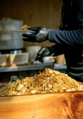 Avrupa 'da sokak yemeği festivali. Markette Asya fast food 'u. Tepside kızarmış tavuklu erişte yığını, eldiven servis eden satıcılar. Taze, canlı, otantik tatlar, hızlı yemek..