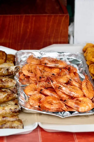Alüminyum folyo tepside ızgara karides ve diğer deniz ürünleri tabakları. Taze pişmiş karidesler deniz ürünleri ziyafetinde yemek için hazır. Sokak yemeği.