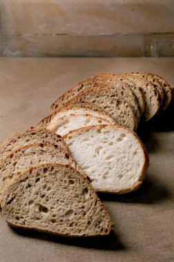 Taze dilimlenmiş zanaatkar ekmeği karışımı beyaz ve kahverengi ahşap üzerinde çoklu tahıllı somun. Ahşap desenli kırsal arkaplan.