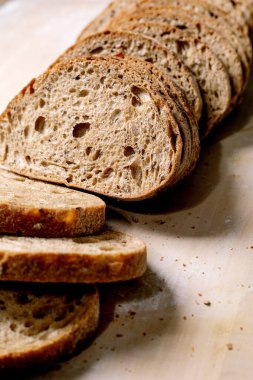 Hafif arka planda dilimlenmiş taze pişmiş tam tahıllı ekmek. Gözenekli, çıtır çıtır kenarlı, sanatsal ekmek. Organik sağlıklı pişirme.