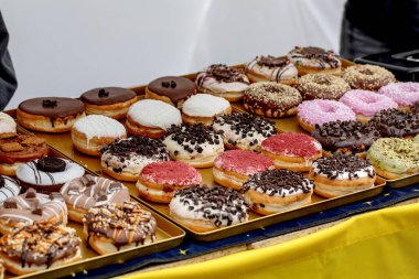 Farklı malzemelerle çeşitli taze çörekler çikolata parçacıkları vanilya jöleli pembe kaplama altın tepside sıralanmış. Tatlı hamur işleri fırında veya kafede sergilenir..