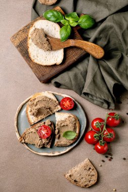 Ev yapımı ciğer ezmesi taze kiraz domatesli fesleğen yaprağı ve seramik tabakla servis edilen ekmek dilimlerine sürülmüş. Kırsal stil aperatifi.