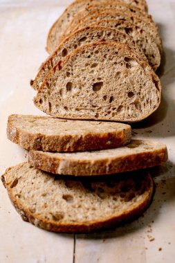 Köy ekmeği dilimleri, gözenekli dokular ve ahşap zemin üzerinde çıtır çıtır çıtır. Kahvaltı ya da sandviç için mükemmel bir ekşi ekmek yakın plan..