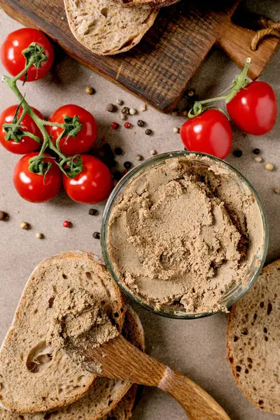 Ev yapımı karaciğer ezmesi taze ekmek dilimleri olgun domatesler ve dağınık biberler. Kırsal ahşap kesim tahtası. Geleneksel aperatif.