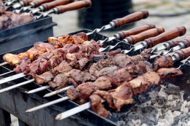Salamura edilmiş et parçaları kızgın kömürün üzerinde ahşap saplı metal şişler üzerinde ızgara yapıyor. Geleneksel barbekü pişirme süreci.