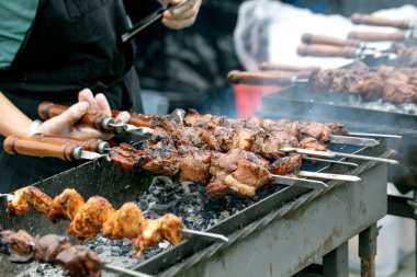 Şef ızgarada et kebabı pişiriyor. Sıcak kömürün üzerine ızgara et parçaları konmuş sulu şişler. Sokak yemekleri festivali barbekü pişirme süreci.