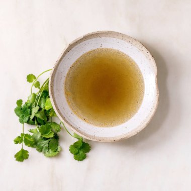 Beyaz mermer masada taze yeşil kişniş demeti ile seramik kasede ev yapımı tavuk ya da ördek çorbası. Düz yat, boşluğu kopyala