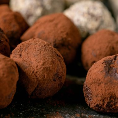 Homemade chocolate cocoa and nuts truffle candy collection on black ceramic plate. Handmade food sweet gifts for any holidays. Close up