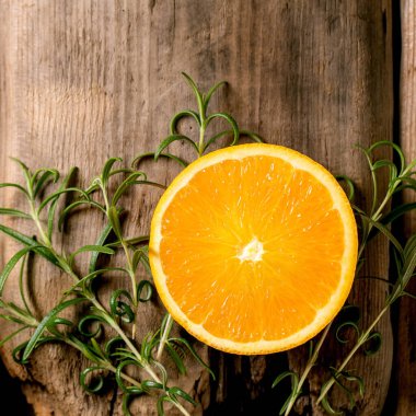 Citrus ve şifalı bitkiler. Eski ahşap zemin üzerinde taze organik dilimlenmiş portakal ve biberiye dalları. Üst görünüm, alanı kopyala