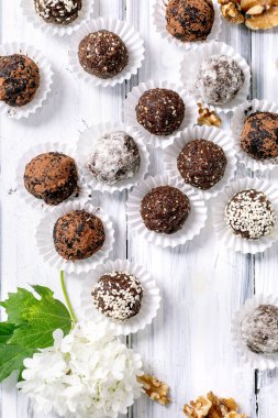 Çeşitli malzemelerle ev yapımı çiğ vejetaryen enerji topları kakao, hindistan cevizi, fındık, beyaz ahşap arka plan. Sağlıklı vejetaryen tatlı..