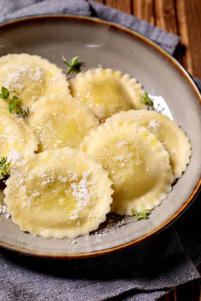 Seramik tabakta servis edilen parmesan peynirli ve kekik otlu ev yapımı ravioli makarnası. Geleneksel İtalyan mutfağı.