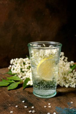 Limon dilimli cam köpüklü su kırsal ahşap masada çiçek açar. Beyaz çiçekli doğal ferahlatıcı içecek.
