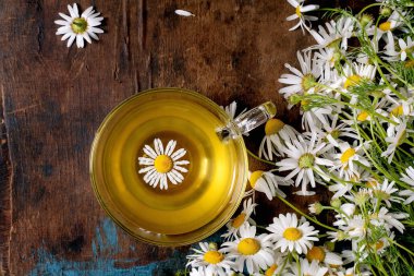 Kırsal arka planda taze papatya çiçekleri ve papatya çayı bitkisel içecek konsepti