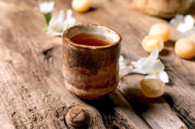 Seramik fincan bitkisel çay, ahşap masa, beyaz çiçekler, sade çiçekler, sağlıklı içecek rahatlama anı.