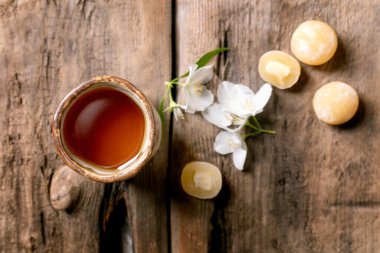 Beyaz yasemin çiçekleri ve geleneksel Asya tatlısı mochi toplarıyla süslenmiş kırsal ahşap masa üzerindeki seramik çay fincanı.