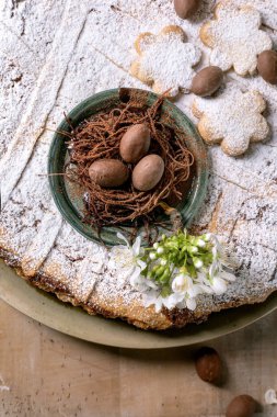 Geleneksel Paskalya tatlısıyla geleneksel Pastiera Napolitano turtası üzerine çikolatalı yumurtalar ve kırsal arka planda beyaz bahar çiçekleri. Neşeli tatlı kompozisyon.