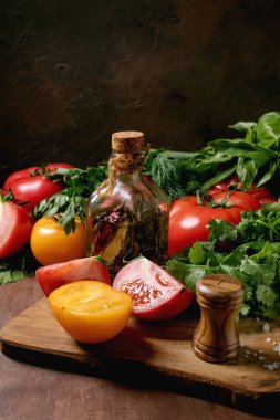 Taze domates bitkileri zeytinyağı şişesi ahşap kesim tahtasının üzerinde. Tuz değirmeni yapraklı sağlıklı yemek malzemeleri.