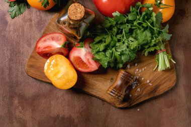 Taze domates bitkileri, ahşap kesme tahtasına yerleştirilmiş tuzlu zeytin yağı. Yemek hazırlamak için sağlıklı malzemeler..