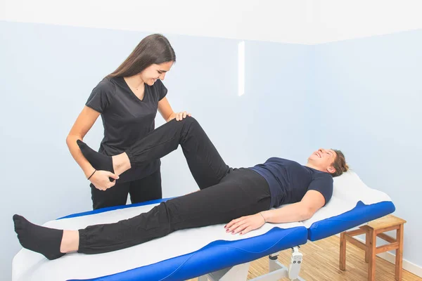 A physical therapist performs lower limb mobilization to a patient