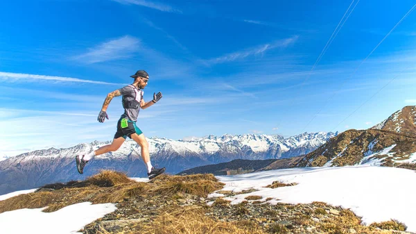 男子山岳走者が草や雪の上を走る — ストック写真