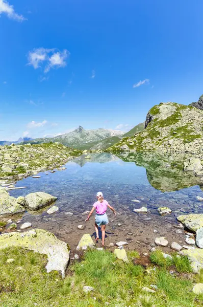 Ein Kleines Mädchen Tritt Mit Den Füßen Einen Kleinen Bergsee lizenzfreie Stockbilder