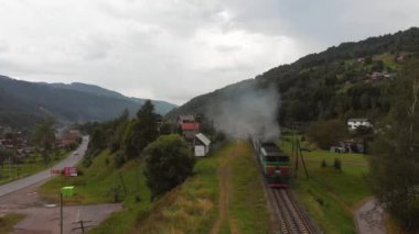 Dizel tren nehir yamacı boyunca uzanan manzaralı araziden demiryolunun her iki tarafındaki yeşil çimlerin arasından geçer. Havadan görüş ve trenin izini sürme. Yüksek kalite 4k görüntü