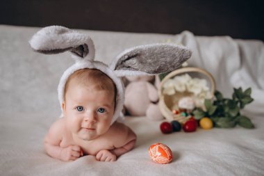 Paskalya 'da tavşan kulağı takan şirin bir bebek. Paskalya yumurtalarına yakın. Kameraya bakar ve gülümser. Yüksek kalite fotoğraf