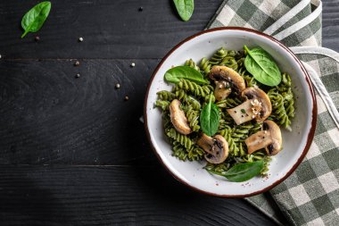 Mantar ve Ispanak Makarnası ve Koyu arkaplanda Vegan Yemeği. Vejetaryen ya da glütensiz diyet. afiş, metin için menü tarifi yeri, üst görünüm.