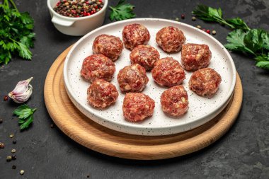 Kesme tahtasında baharatlı taze çiğ et köfteleri koyu arkaplan, pankart, menü, metin için tarif yeri, üst görünüm.