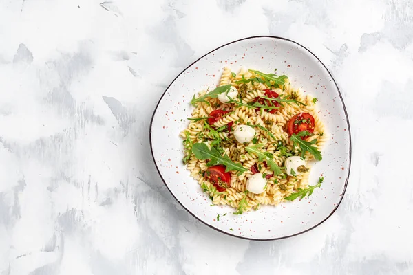 stock image Italian cold pasta salad. Fusilli, tomato, mozzarella, olive, arugula. Pasta alla caprese on a dark background, Restaurant menu, dieting, cookbook recipe top view,