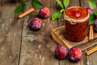 Jar with homemade plum jam on a wooden background. banner, menu, recipe place for text.