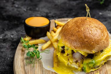 Homemade burger with grilled meat, vegetables, sauce on rustic dark background. fast food and junk food concept.