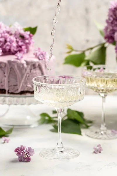 Delicious prosecco, champagne, wine with berry mousse cake bouquet of purple blooming lilacs, French cuisine, postcard, background.