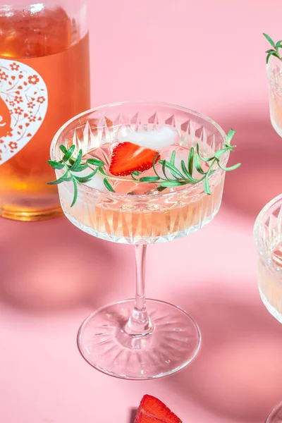 stock image refreshing fruit cocktail or punch with wine champagne, strawberries, ice and rosemary on pink background. Freeze motion splash drops of cocktail.