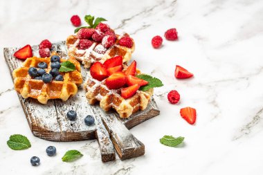 Hafif arka planda taze meyveli Belçika waffleları. Uzun afiş biçimi. en üstteki görünüm .