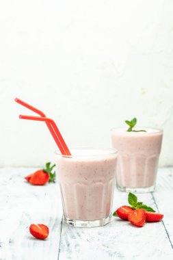 Two Glass with tasty strawberry smoothie with berries and yogurt in glass jar on white background. Vegetarian healthy drink.