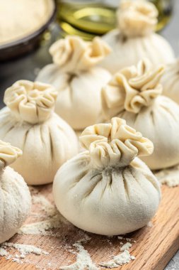 Çiğ khinkali ile tahta kesmek et, yarı bitmiş ürünler hamur köftesi. Khinkali pişirmek. Ulusal Gürcü mutfağı. dikey görüntü. en üstteki görünüm.