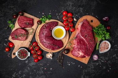 Taze ve çiğ et. Biftek ve baharatlı sığır filetosu koyu arka planda, pankartta, menüde, metin için yemek pişirmeye hazır.,