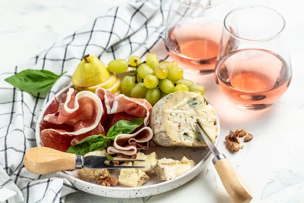 Pink wine rose aged cheese Camembert cheese nuts honey grapes, Pears, blue cheese glasses of wine. French cuisine, Delicious food wine snacks assorted,