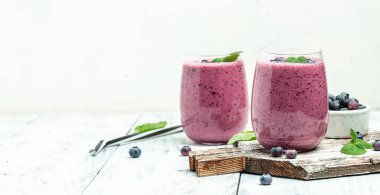 İki bardak taze böğürtlen yoğurtlu meyve suyu taze yaban mersini ya da hafif arkaplanda yaban mersini. Uzun afiş biçimi. en üstteki görünüm.