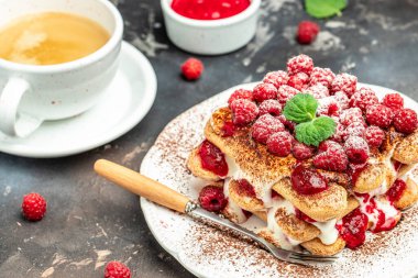 Böğürtlenli tiramisu, bisküvi, krema ve taze böğürtlen. Koyu arkaplanda ahududu olan tiramisu,