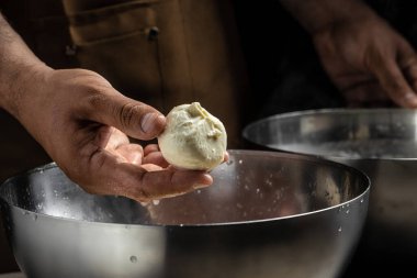 Küçük bir aile mandırasında çalışan bir adam peynir yapmanın son adımlarını işliyor. İtalyan sert peyniri silano veya caciocavallo, mozzarella.